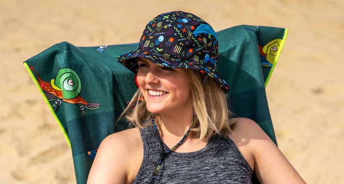 Woman sitting on a beach wearing a black bucket hat