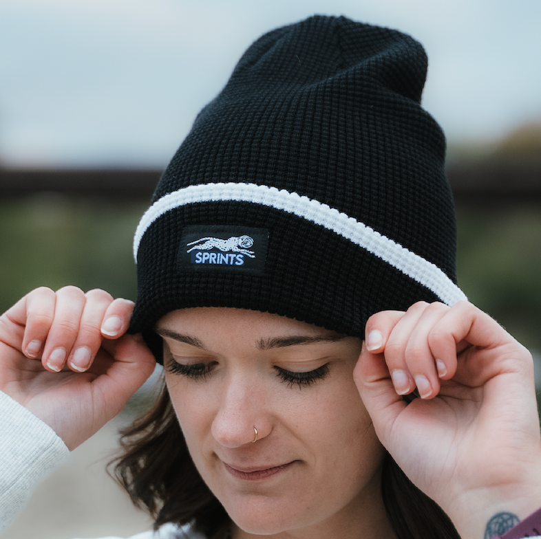 woman is wearing a merino winter running hat on a trail setting