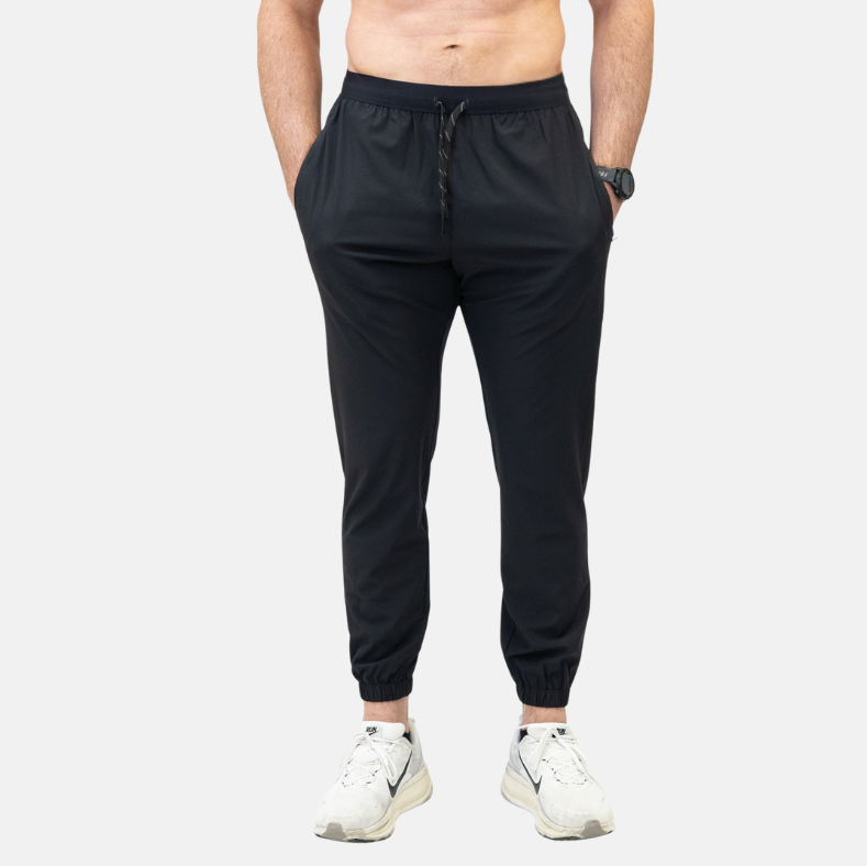 Person wearing black jogger pants on a white background