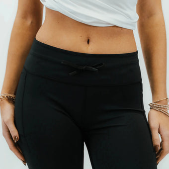 Person wearing a white crop top and black leggings on a plain background