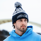 Person wearing a blue hoodie and a beanie with 'Spring' branding against a blurred background