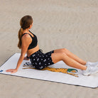 Woman exercising on a branded mat in a sandy area